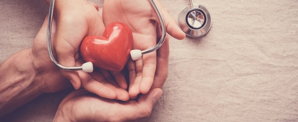 child and adult holding red heart with stethoscope, heart health
