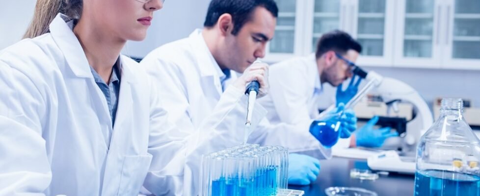 Science student using pipette in the lab to fill test tubes at the university