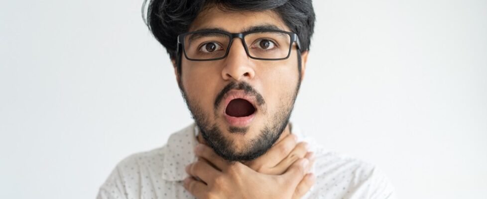 Scared Indian man keeping mouth open and chocking himself