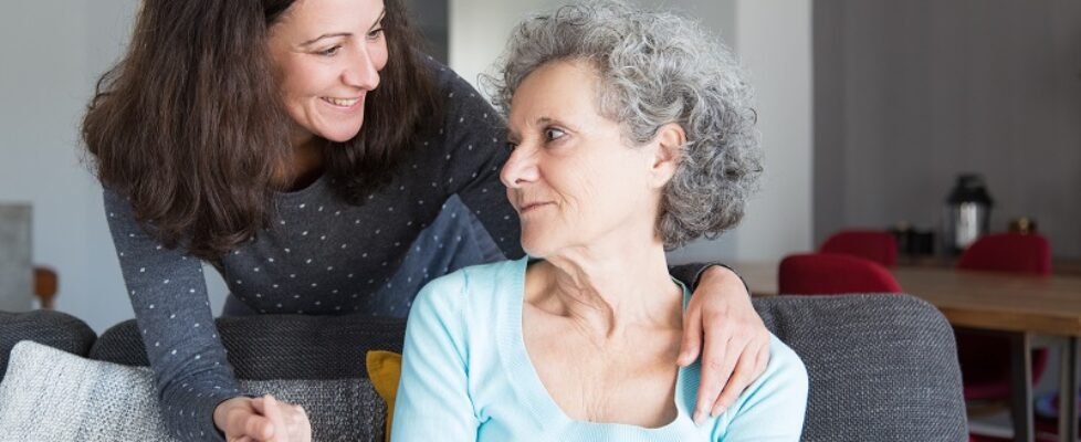 Smiling adult daughter supporting sad senior mother