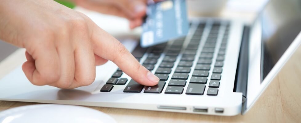 Hands holding a credit card and using laptop computer for online