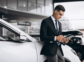 Young handsome man in car showroom