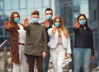 People wearing protective masks are showing stop sign by hands