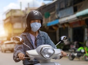 Woman riding a motorcycle wearing a mask in the city