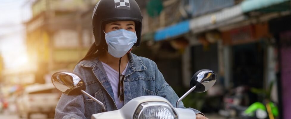 Woman riding a motorcycle wearing a mask in the city