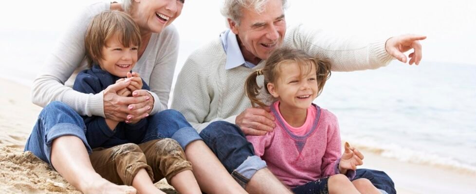 Grandparents And Grandchildren Sitting On Beach Together