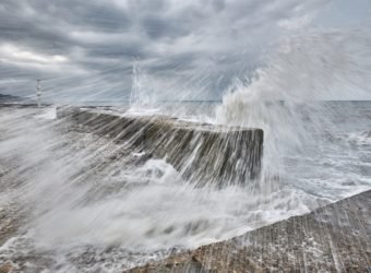 Splashes from the raging waves fly to the shore, in motion