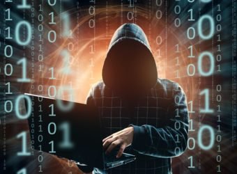 A man in a hood, a hacker, a hacker attack, a silhouette of a man, holds a laptop, threatens. mixed media. The concept of sudden attack, cryptography, data security.