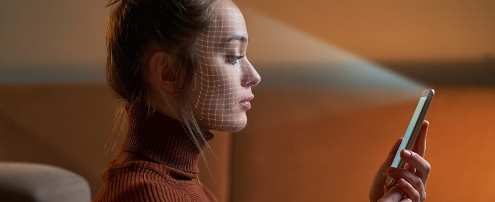 Female scans face using facial recognition system on smartphone