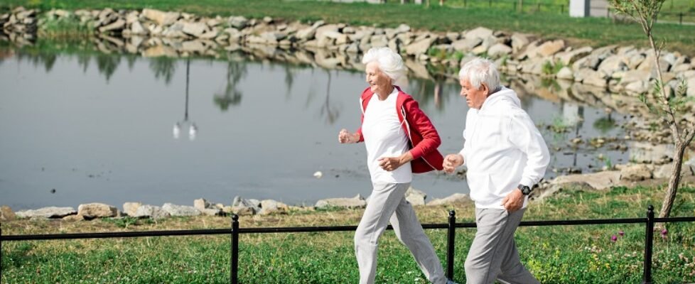Active Senior Couple Running by Lake