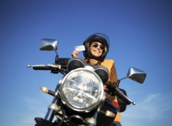Motorcycle riding school and courses. Student with helmet and reflective vest riding motorcycle on class.