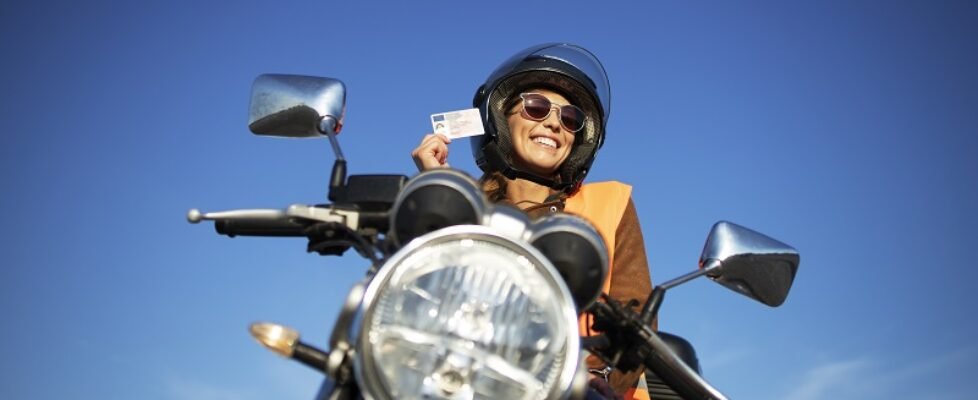 Motorcycle riding school and courses. Student with helmet and reflective vest riding motorcycle on class.
