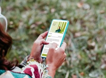 back rear view of woman relaxing in hammock and listening to music on mobile phone and headset. autumn season. camping concept