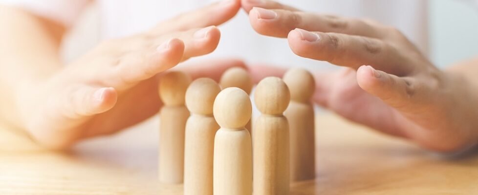 Protection people health and insurance concept. Hand shield protect wooden human on table