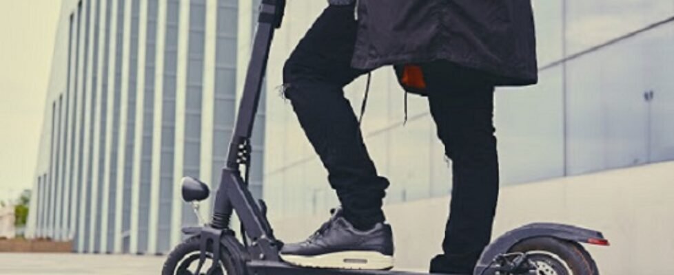 Close up image of a man on an electric scooter.