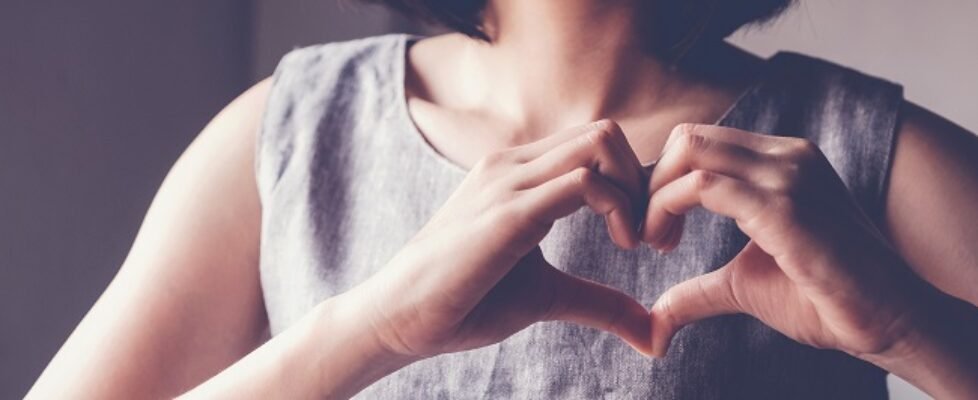 Happy Asian young woman making her hands in heart shape, heart h