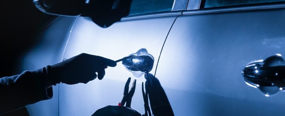 Car thief using a tool to break into a car