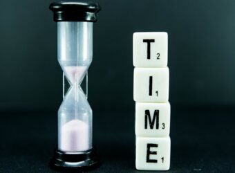 Dice reading TIME with a sand clock beside