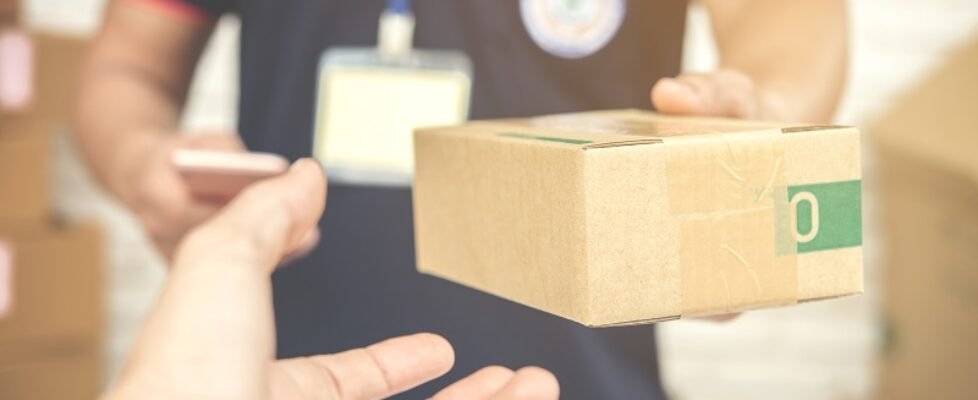 delivery man smiling and holding a cardboard box
