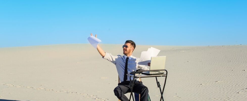 Businessman using laptop in a desert