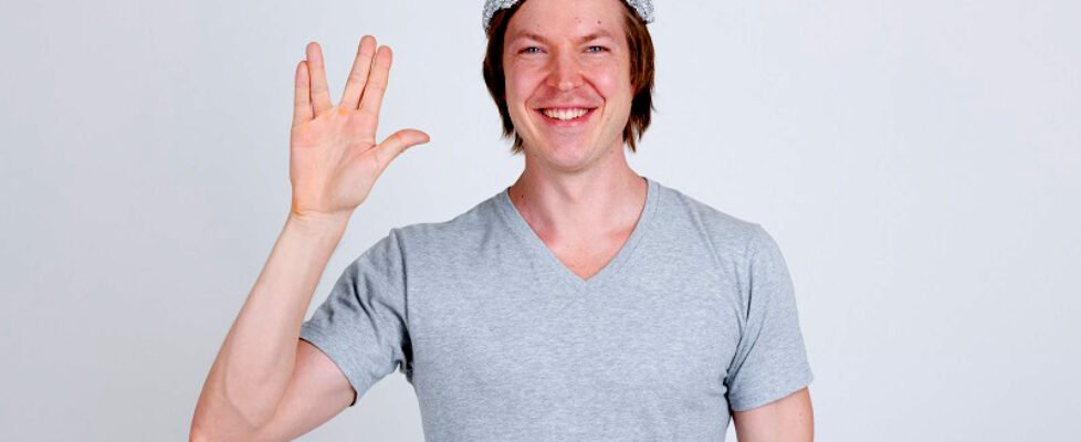 Happy young man wearing tin foil hat as conspiracy theory concept showing Vulcan salute in Star Trek