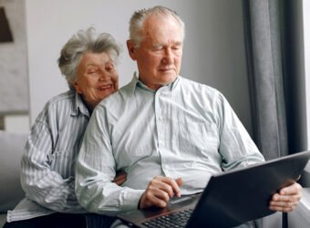 Elegant old couple sitting at home and using a laptop