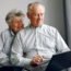 Elegant old couple sitting at home and using a laptop