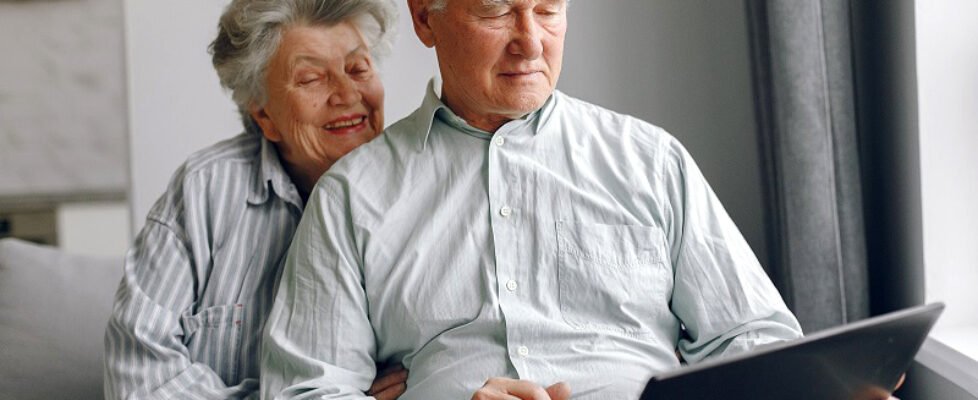 Elegant old couple sitting at home and using a laptop
