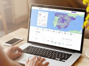 Rear view of high school girl using laptop for doing homework, browsing Internet, searching for required information, sitting at desk with mobile phone with copy space screen lying next to her