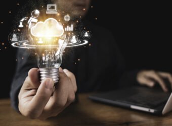 Hand holding lightbulb with cloud computing and technology icons