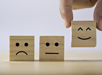 Hand putting smiley emotion to among normal and sad emotion whic