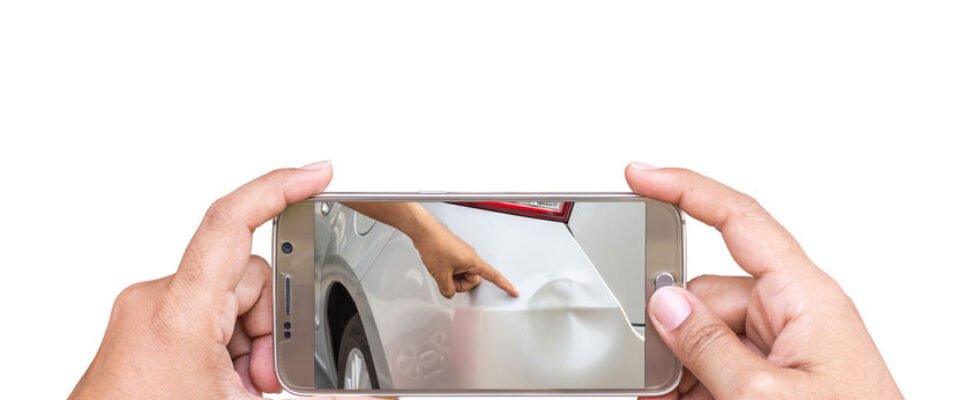 Hand of woman holding smartphone and take photo of car accident