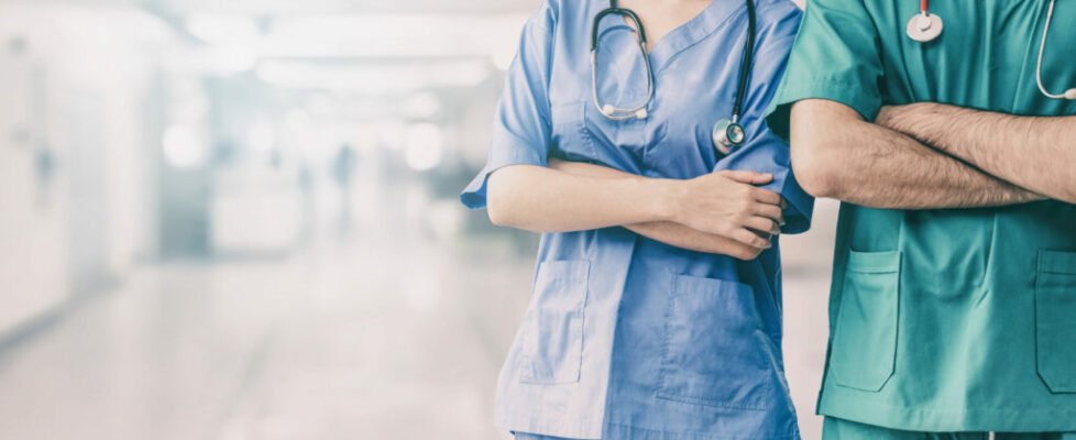 Doctor and surgeon with arms crossed in hospital.