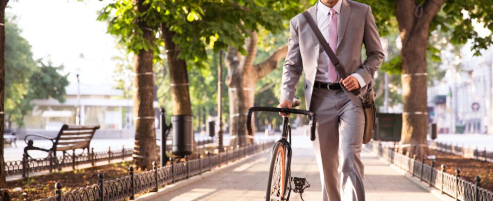 Pensive,Young,Businessman,Walking,With,Bicycle,On,The,Street,In