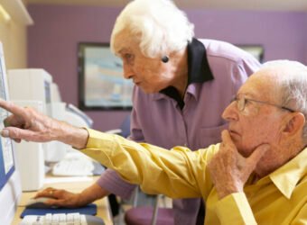Senior woman helping senior man use computer