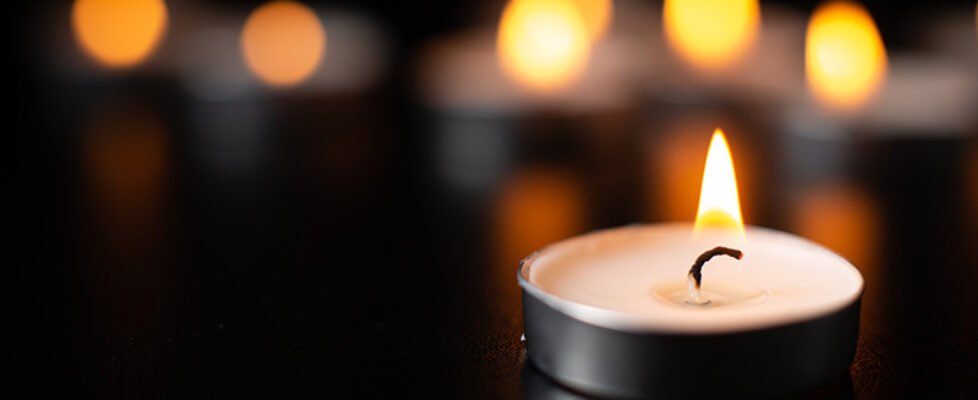 front view of burning candles on pitch black surface funeral war