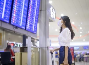 A traveller woman is wearing protective mask in International airport, travel under Covid-19 pandemic, safety travels, social distancing protocol, New normal travel concept