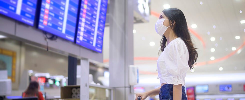 A traveller woman is wearing protective mask in International airport, travel under Covid-19 pandemic, safety travels, social distancing protocol, New normal travel concept