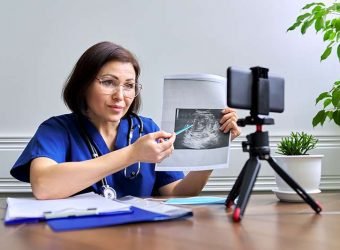 Mature confident female doctor making video consultation using smartphone