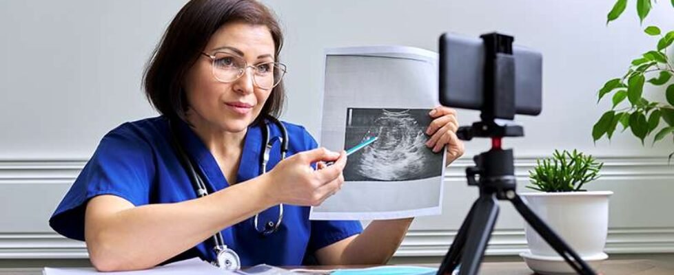 Mature confident female doctor making video consultation using smartphone