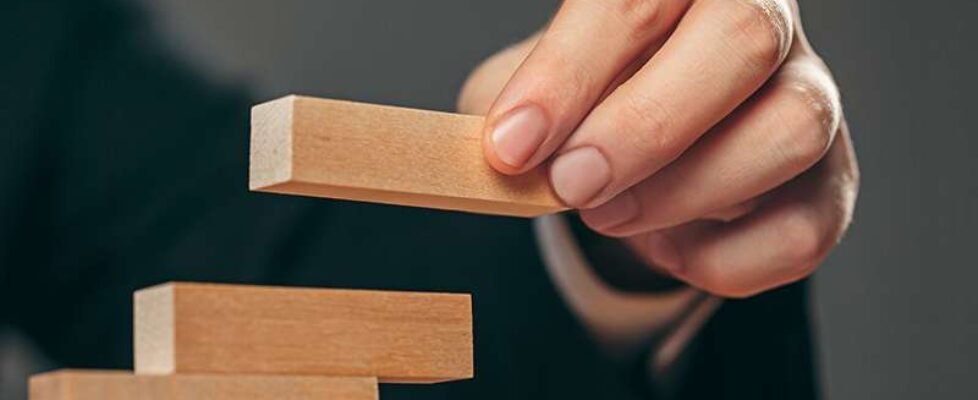 Man and wooden cubes on table. Management concept
