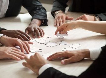 Close up of multiethnic team solving blank puzzle game.