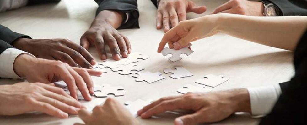 Close up of multiethnic team solving blank puzzle game.