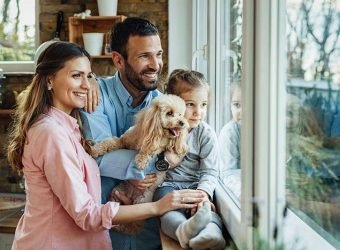 Happy family with a dog looking through the window at home.