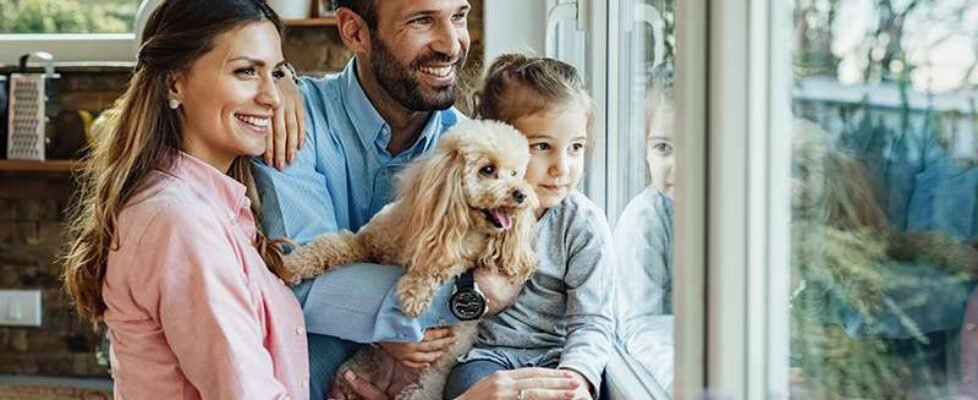 Happy family with a dog looking through the window at home.