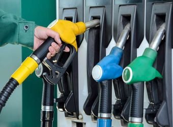 Close-up of a man hand using a fuel nozzle at a gas station.