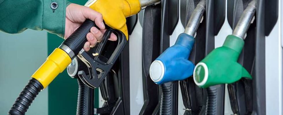 Close-up of a man hand using a fuel nozzle at a gas station.