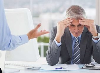 Frustrated businessman sitting with hands on forehead