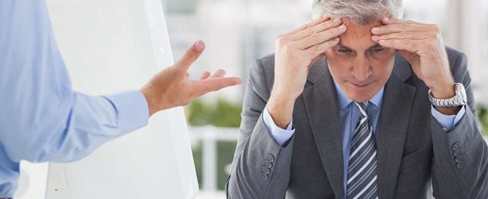 Frustrated businessman sitting with hands on forehead