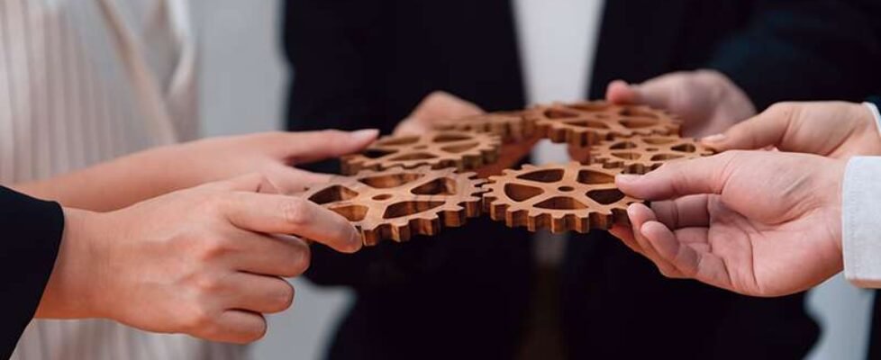 Group of people making chain of gears into collective form for h